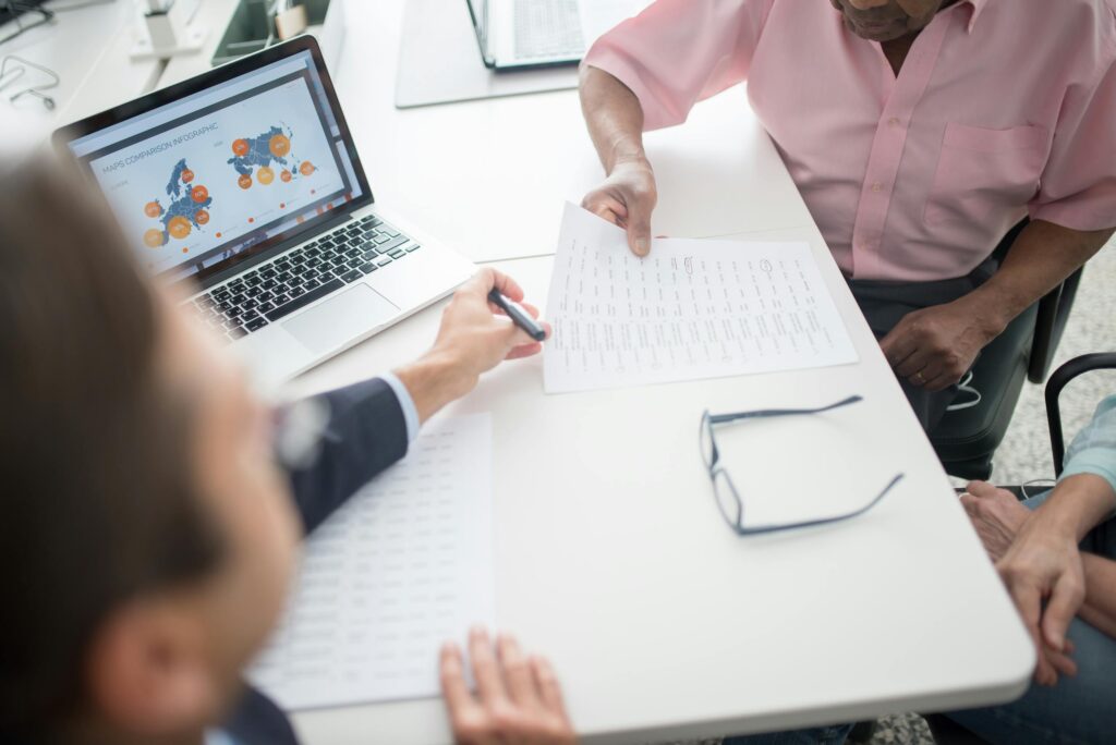 Senior couple reviewing documents with consultant at office desk with laptop.